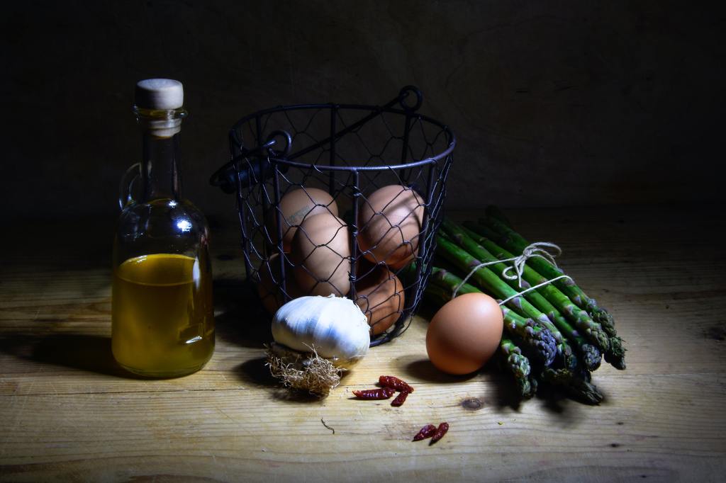 Olive oil, egs and asparagus on a tabe representing heathy ingredients